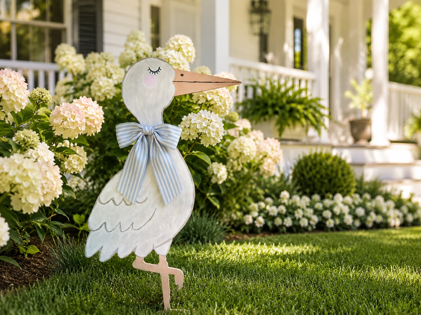 Blue bow stork yard announcement displayed in front of a white Charlotte home with flowers