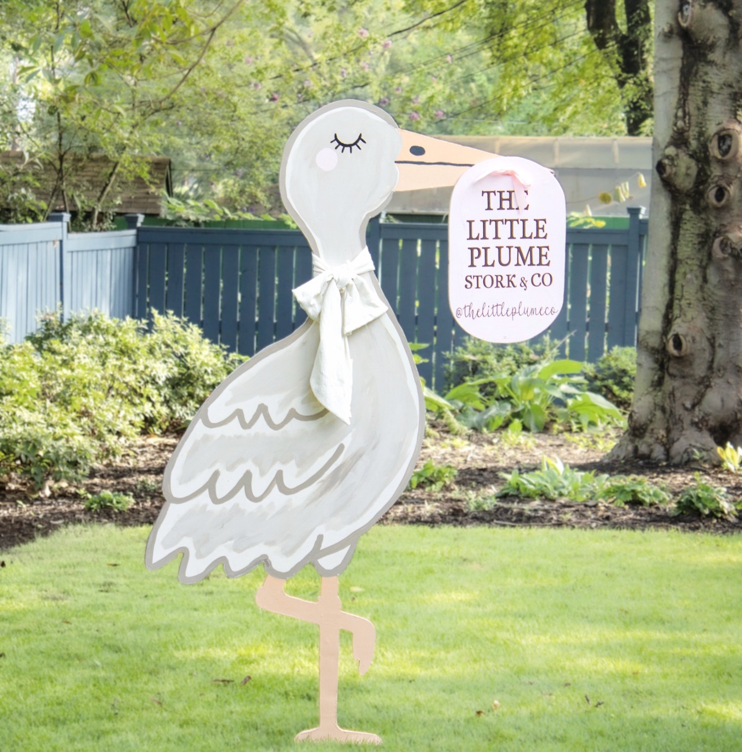 The Little Plume stork yard announcement in a garden